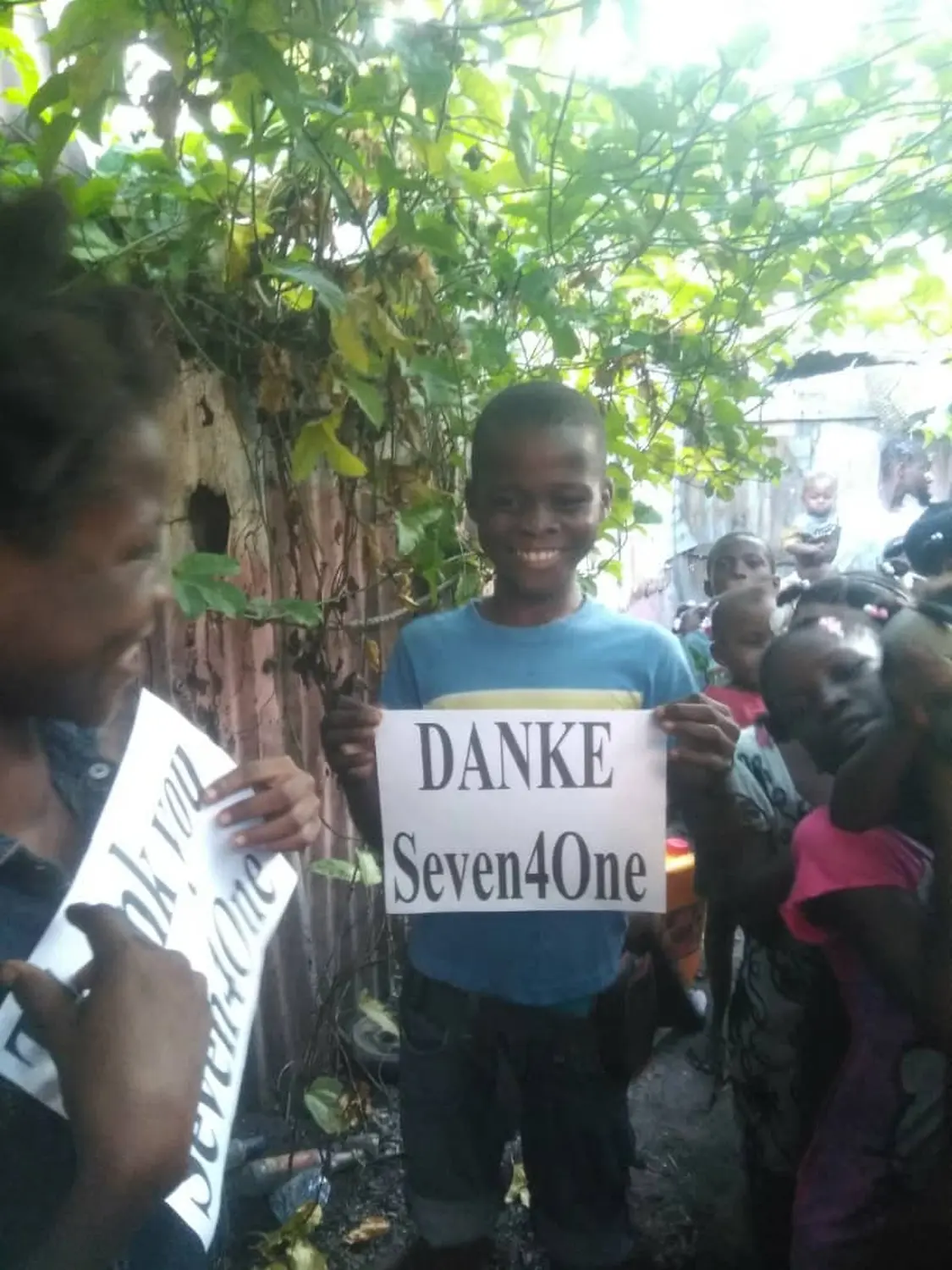 Seven4ONE - Kinder halten ein bedrucktes „Thank You Seven4ONE e.V.“-Papier in der Hand