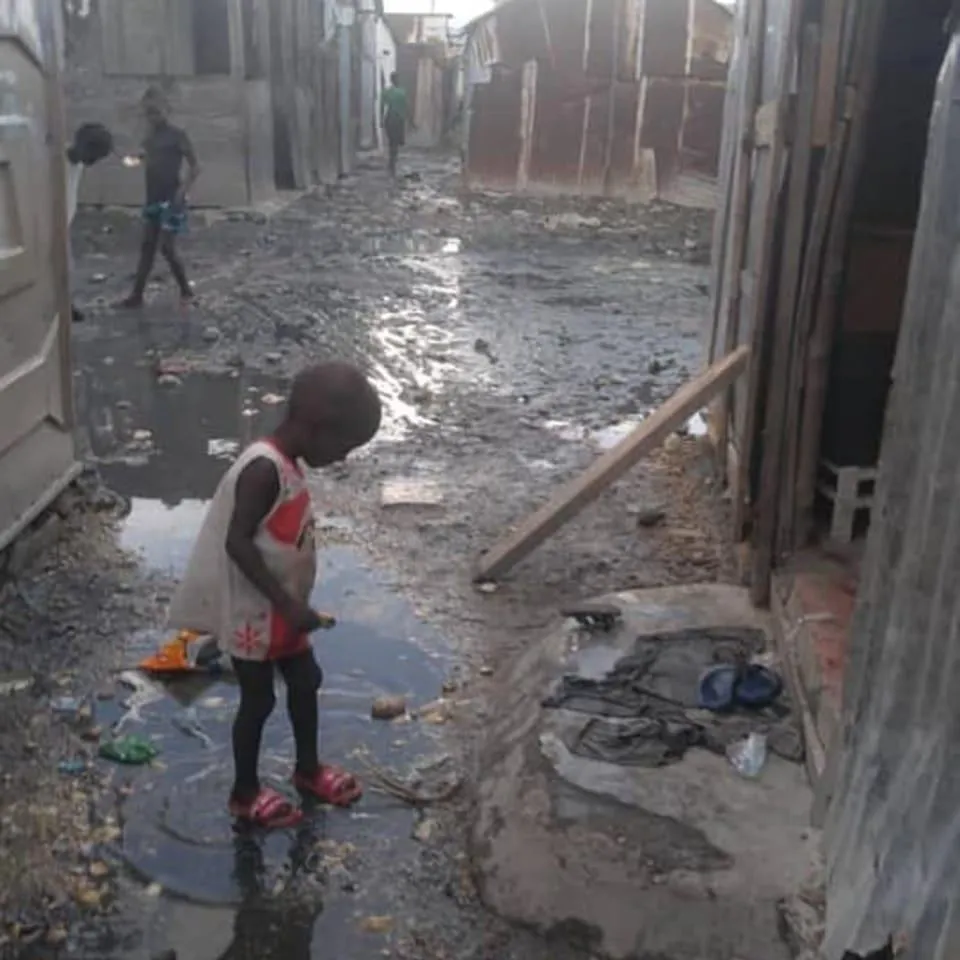 Seven4ONE - ein afrikanisches Kind außerhalb des Tierheims, das in eine Wasserpfütze springt